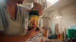 A woman opening a jar of chicken bouillon in a light-filled kitchen